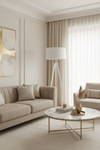 Candeeiro de pé branco em sala de estar luxuosa com sofá em veludo bege e mesa de mármore